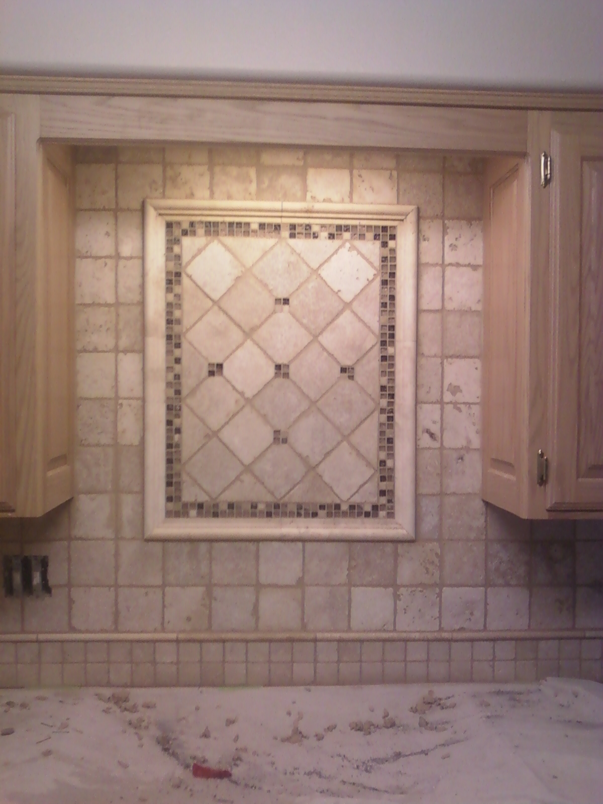 Kitchen backsplash tiled with tumbled marble, with mural and border